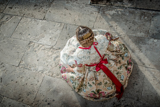 Woman from Valencia with the costume of the traditional festivals. Fallera in her gold-colored dress, sitting in the Serrano Towers

