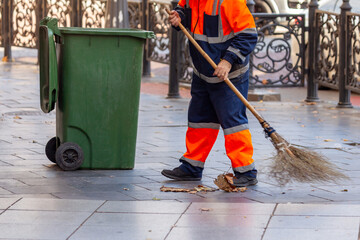 Janitor works in the street with a broom