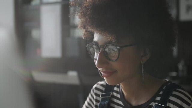 Close Up Young Woman in Fashion Glasses Eye Looking Monitor, Surfing Internet. Stylish Female Working With Laptop or Tablet From Home in Her Home Office. The Monitor Screen Is Reflected In The Glases