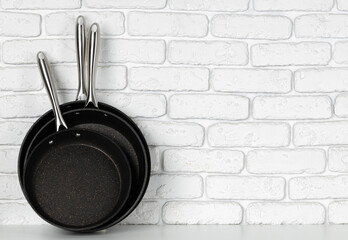 Set of cooking pans against white brick wall