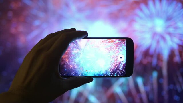 Person taking picture of the fireworks exploding show in 4K