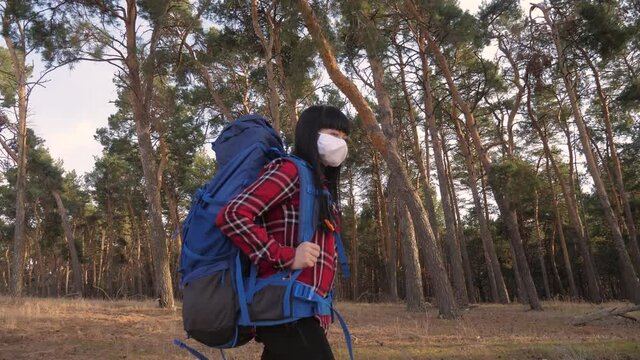tourist hiker girl goes for a walk near a hiking lifestyle backpack forest park. concept pandemic virus epidemic world catastrophe infection covid
