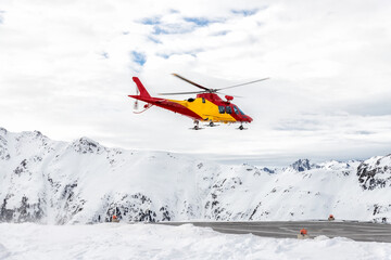 Fototapeta na wymiar Mountain ski life rescue medic helicopter taking-off from station helipad to search injured skiers and help at accident. Emergency chopper at austrian alpine skiing resort. Alps landsape