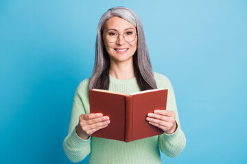 Photo portrait of retired woman holding red book in two hands isolated on pastel light blue colored background