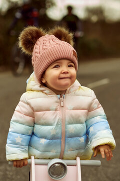 A 1 year old baby girl is with a pink motorcycle outside