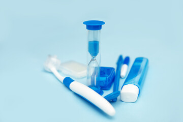 Oral hygiene while wearing braces, braces, home care kit, dental instruments, dental floss, toothbrushes, hourglass. Dental concept on a blue background. Front View