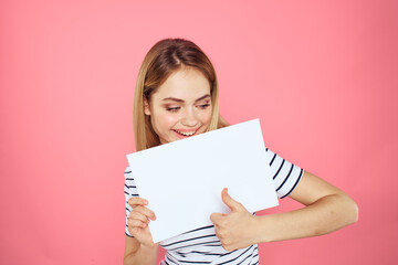 Fototapeta na wymiar woman holding white sheet in her hands striped t-shirt emotions pink background