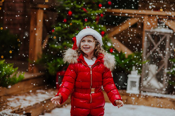 Girl smiling on the wooden terrace with Christmas background. Snowing.