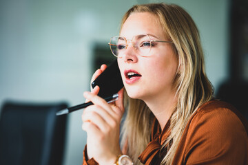 Frauen in Chefetagen, junge Managerin verhandelt am Telefon mit Geschäftspartnern - Symbolfoto.