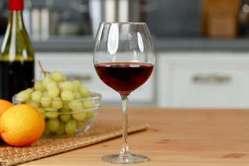 Glass of red wine and oranges on kitchen counter