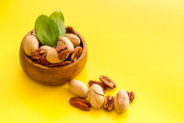 Pecan nuts with leaves in bowl on the table, close up