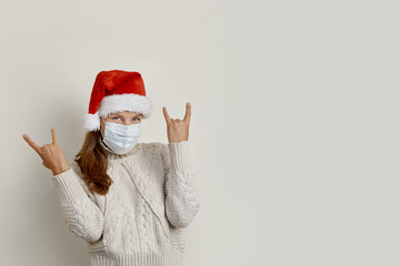Fototapeta na wymiar Young beautiful woman wearing red santa hat over isolated beige background shouting with crazy expression doing rock symbol with hands up