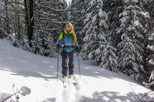 Smiling young female hiker splitboarding on snow covered mountain