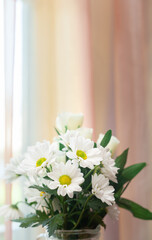 White chrysanthemums and white roses bouquet in the vase near the home window with yellow curtains. Vertical frame. Soft focus.