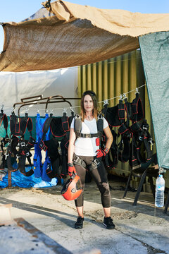 Young female skydiver with parachute backpack, gloves and helmet