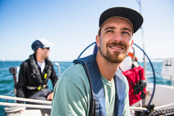 Man smiling during a family sail on sunny summer day