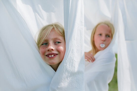 Children play hide and seek among the washed bed linen