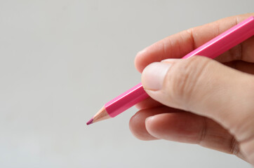 hand holding pink color pencil