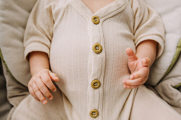 Close up of a big full baby belly in cream colored outfit with buttons