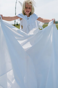 village child with blond hair hangs up the washed laundry