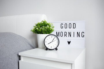 good morning concept - close up of alarm clock, houseplant and lightbox with 