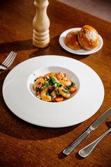 Fresh salad plate with shrimp, tomato and mixed greens on wooden background close up. Healthy food. Clean eating.