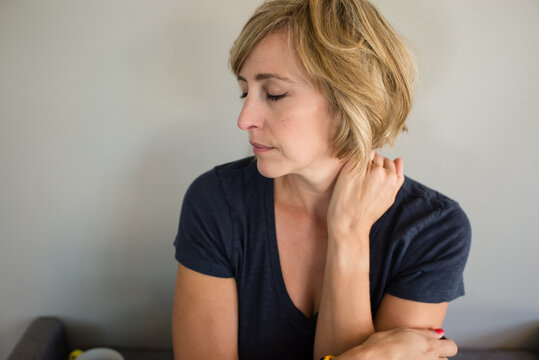Side View of Middle Aged Woman with Eyes Closed Indoors Against Wall