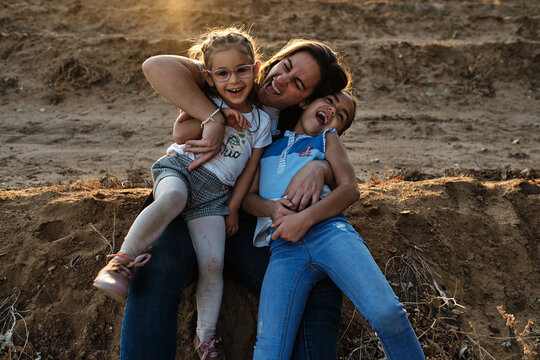 a mother sitting on the field plays with her daughters