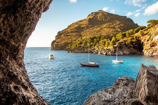 Sa Calobra beach view from a cave with luxury boats in Majorca, Spain
