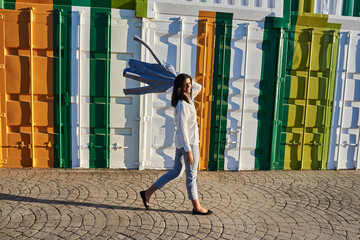 Woman with a jacket on her shoulder walking down the street.