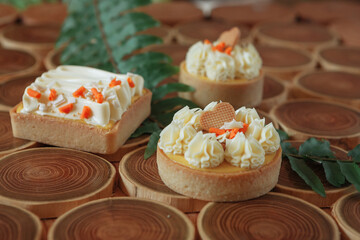 dessert, cheesecake with mango and passion fruit in the form of brownies with mousse on top. Decorated with cookies in the form of a heart. On a wooden table in a white plate