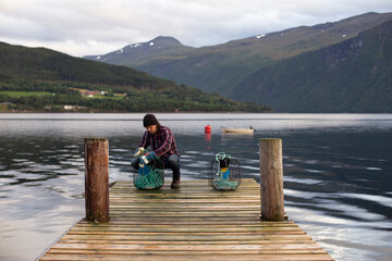 A Norwegian working on some crab pots on a dock by the fjord