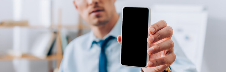 Cropped view of businessman showing smartphone with blank screen, banner