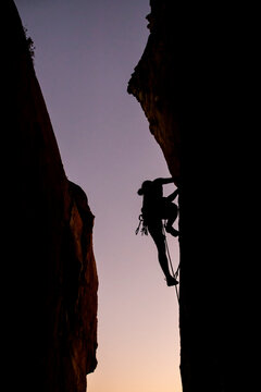 Beautiful view to silhouette of man climbing during sunset