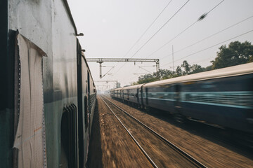 Ordinary express train on a trip from New Delhi to Agra just passing by another train the opposite direction.