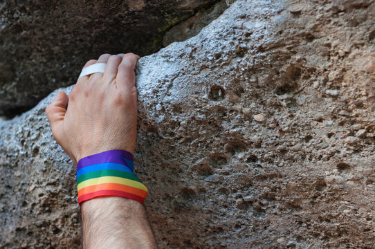 climbing hand with gay pride bracelet with title background