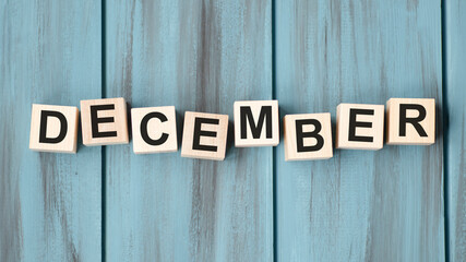 Text december on wooden cubes on blue background