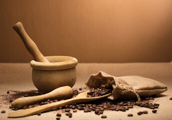 wooden spoon, with natural coffee beans and ground powder, with wooden mortar, on raffia cloth and brown background