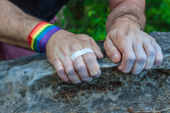 Two-handed close-up of a climber with the gay pride bracelet.