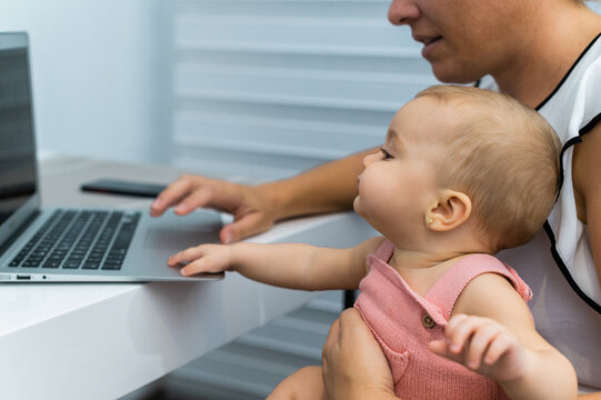 MOM TELEWORKING AND WITH HER BABY IN ARMS