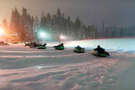 A group of people slide down a snowhilll on tubes in Oregon.