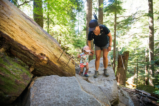 Pregnant Mother Helps Her Two Year Old Hiking On Rocky Terrain.