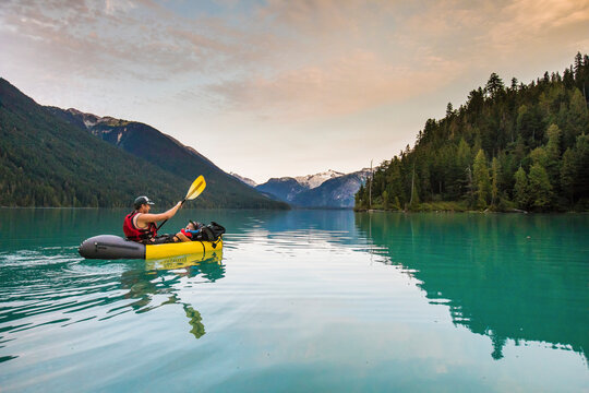 Father paddling inflatable boat with son on lake.