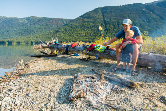 Father and son roast marshmallows over fire during a father son trip