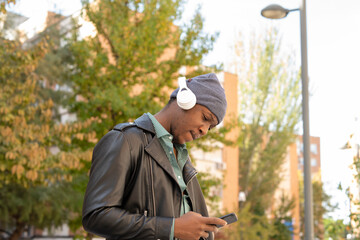 young african man in the city listening to music from his mobile phone