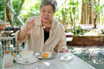 old asian elderly senior elder woman eating cheesecake at restaurant.
