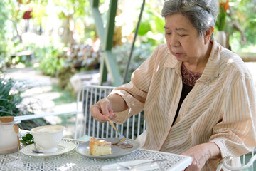 old asian elderly senior elder woman eating cheesecake at restaurant.