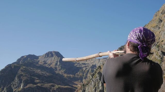 A man makes a sound from a natural didgeridoo in the Caucasus mountains.