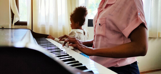 Mother is teaching and learning to play the piano at home.