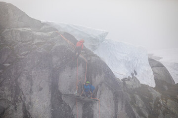 Climbers rappelling onto portaledge as stormy weather blows in.